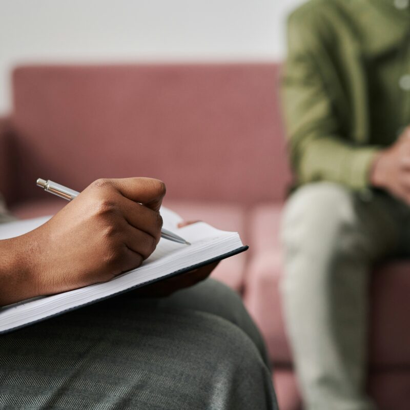 therapist writing notes during a counseling session for addiction and mental health treatment